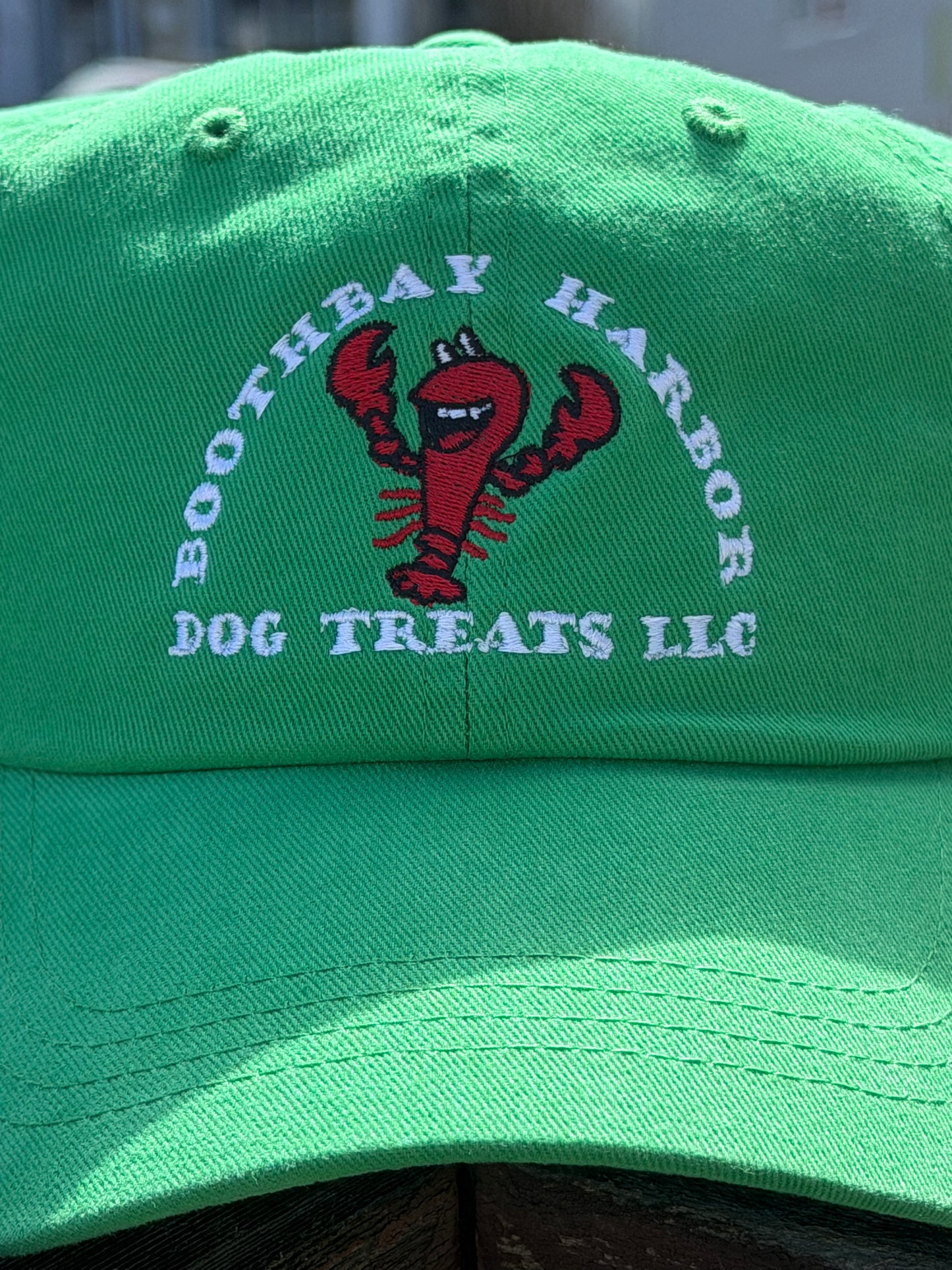 Close up of Kelly green Boothbay Harbor Dog Treats dad hat with embroidered red lobster logo