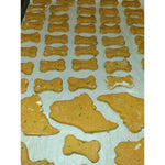 A parchment-lined baking sheet filled with unbaked treats cut into fun, bite-sized bone and state of Maine shapes. Thumbnail