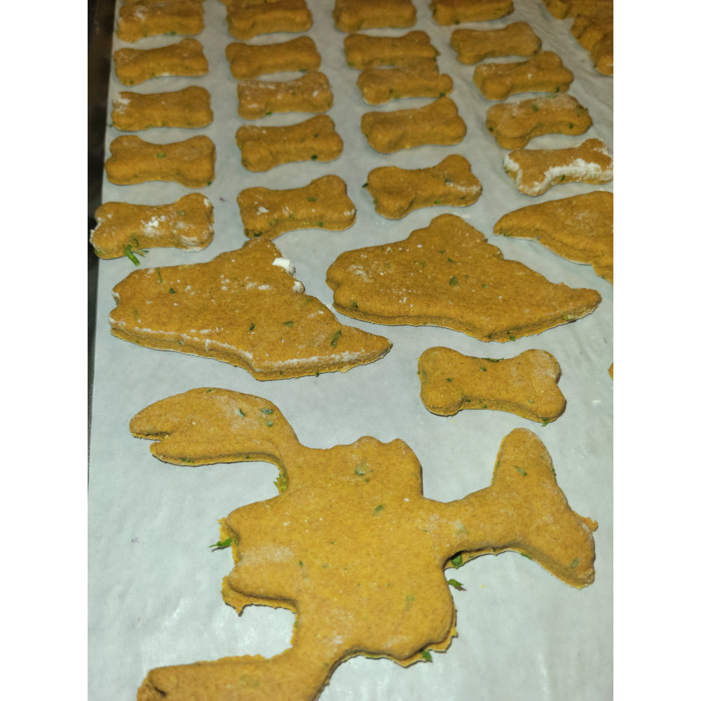 Close-up of raw dog treats on a baking pan, featuring unique, locally inspired shapes including small bones, the state of Maine, and lobsters.