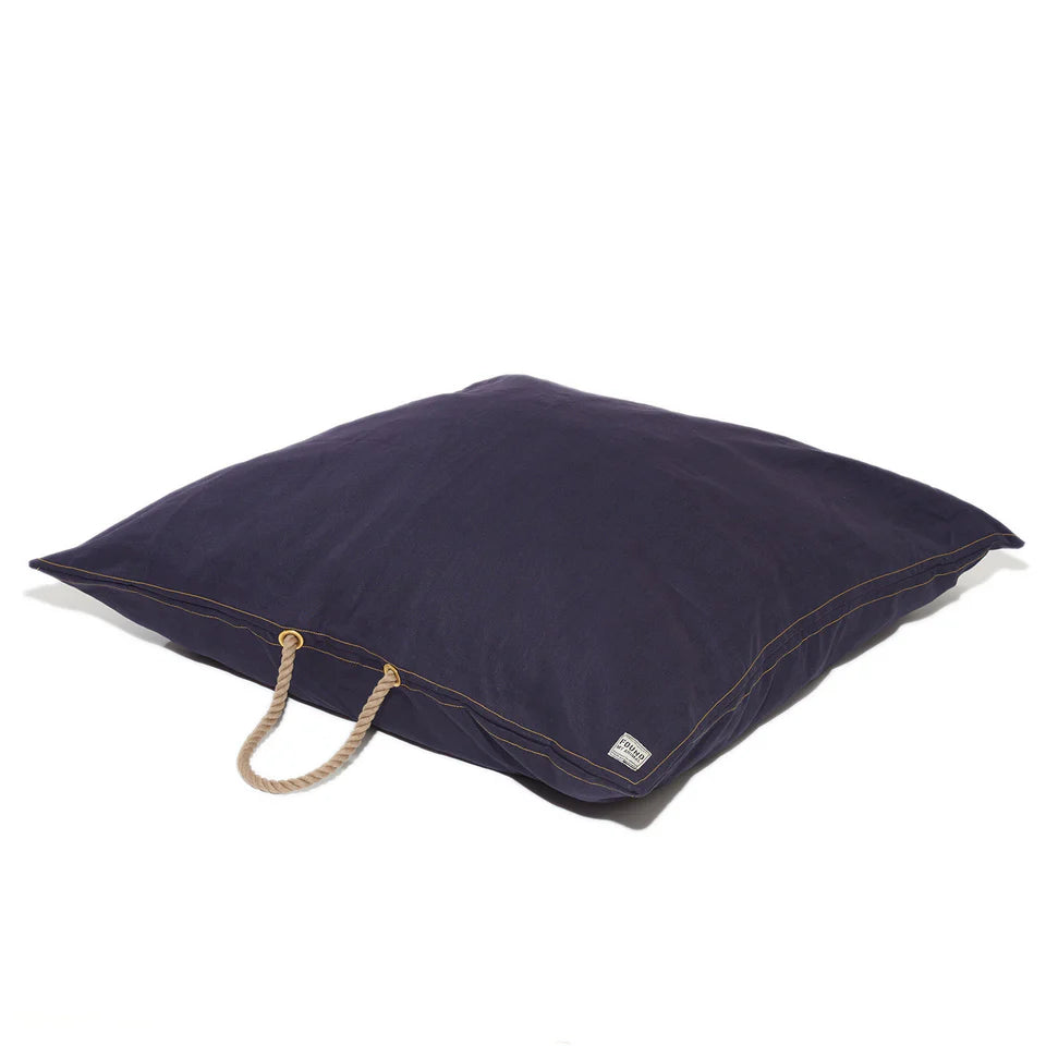 Square navy blue dog bed with a rope handle and brass grommets on a white background.