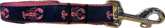A horizontal view of a dog leash featuring a dark navy blue fabric ribbon with a repeating pink lobster pattern, stitched onto contrasting vibrant pink nylon webbing and attached to a silver metal swivel snap hook.